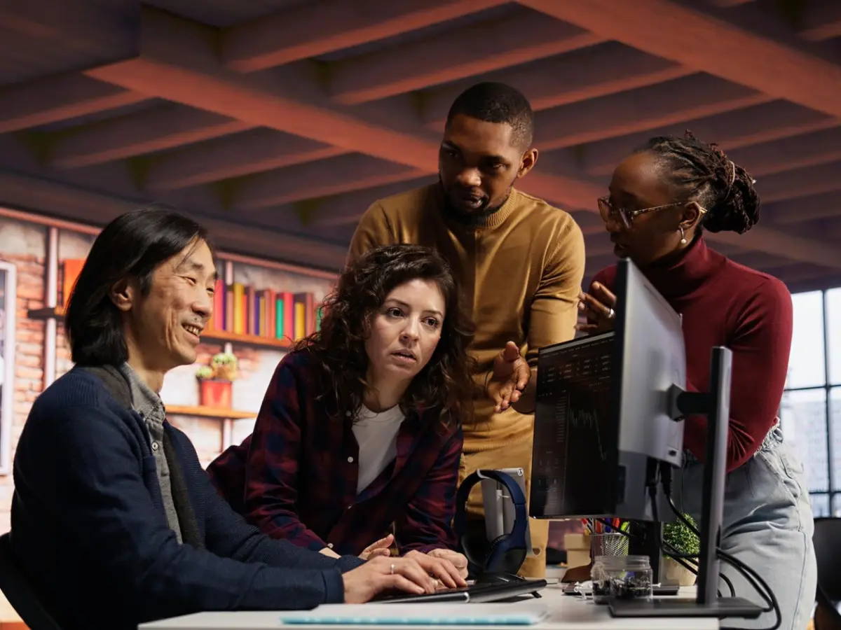 Team collaborating around a desktop monitor